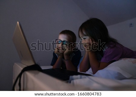 Brother and sister looking cartoons at computer in bedroom