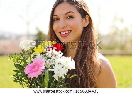 Portrait of a romantic smiling young woman with flower bouquet outdoors