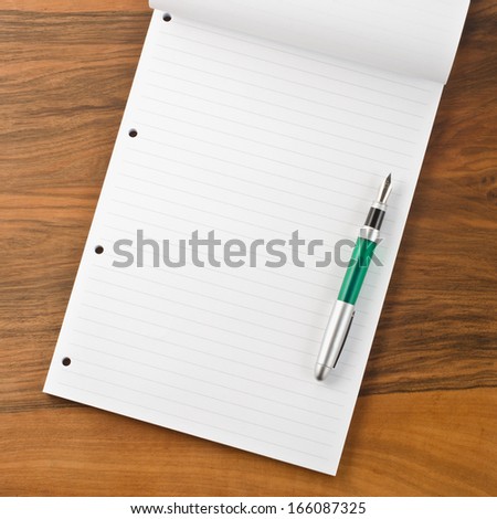 Paper notebook with pen on wooden background  
