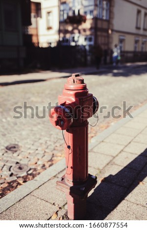 red fire hydrant in a city setting.