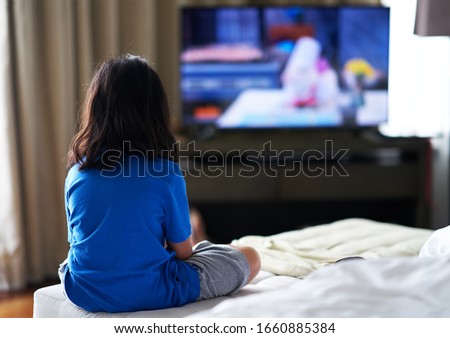 Girl sit on bed focus watching TV in room alone in family careless and TV addiction concept