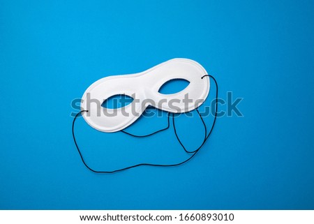 white mask on blue paper background