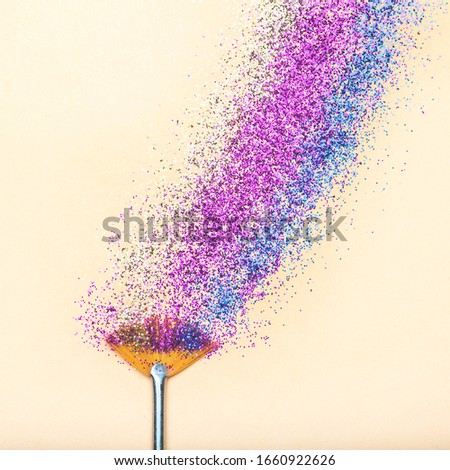 Brush with colorful glitter on yellow background