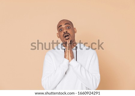 Pensive African guy with a white sweatshirt on a yellow background