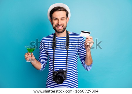 I'll pay. Photo of attractive guy photographer hold digital camera traveler buy credit card green cocktail wear striped sailor shirt vest cap isolated blue color background
