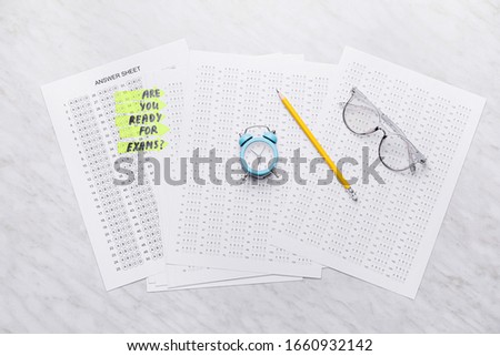Answer sheet forms with alarm clock on white background. Concept of preparation for exam