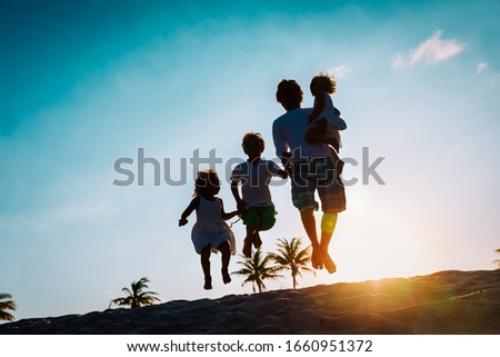 happy father with kids jumping from joy at sunset