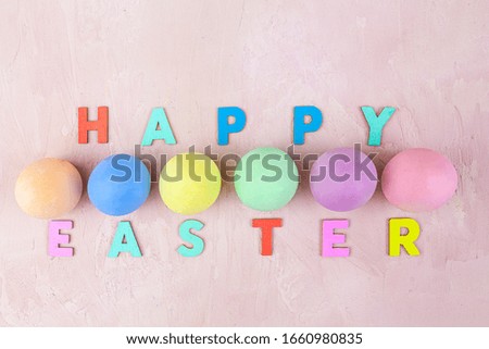 Happy Easter text with colorful eggs on pink background - top view