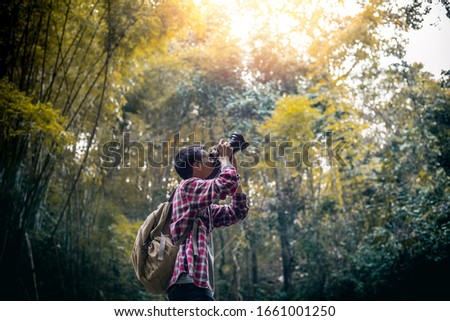 Tourists man or photographer hand holding dslr camera watching taking capture photo nature tree on outdoor in beautiful forest