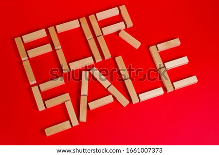 The inscription "For sale", composed of wooden bars on a red background. Background for shops and commerce.