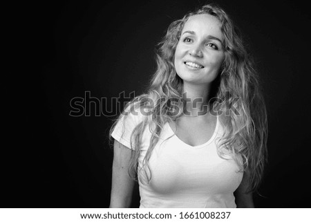 Young beautiful woman with long wavy blond hair against gray background
