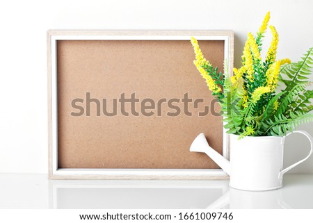 Frame and flowers on the table. White colors. Greeting card. Background with copy space. Mock up.