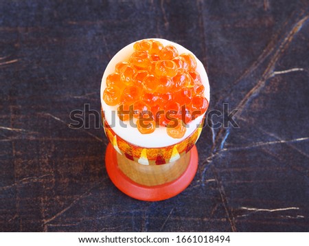 One portion of a large red caviar of fish keta with an egg in a wooden stand on a dark background, closeup. Bright picture with delicious seafood for dinner for the holiday.
