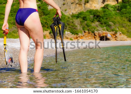 Unrecognizable mature female with snorkel equipment flippers and snorkeling mask tube on beach sea shore. Summer vacation swimming fun concept.