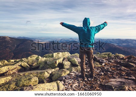 Young man traveler stands on top of a mountain.