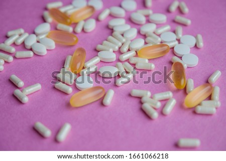 White and yellow pills on a pink background. Dosage of medication. Assorted pills in the shape of a heart. oral contraceptives. Cardiology