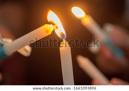 Lighting a candle using the torch from another candle. A practice done during Christian baptisms. Royalty-Free Stock Photo #1661093896