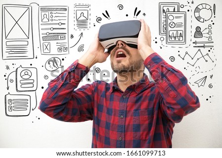 Hand drawn UI or UX pictures with man experiencing VR headset. Studio shot of young tester looking up while testing virtual reality glasses. Technology concept