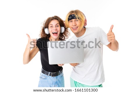 Stylish caucasian blonde man and young woman shows laptop and listen to music isolated on white background