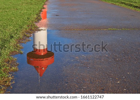 top of small lighthouse at Ritzenbütteler Sand, municipality Lemwerder (district Wesermarsch, Germany) on a sunny spring day with blue sky reflecting in a puddle on a footpath