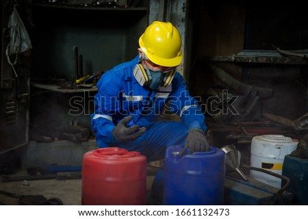 A Worker industry wearing safety uniform ,black gloves and gas mask under checking chemical tank in industry factory work Royalty-Free Stock Photo #1661132473