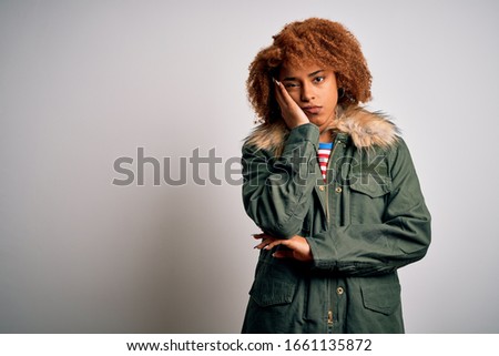 Young beautiful African American woman with curly hair wearing green casual winter coat thinking looking tired and bored with depression problems with crossed arms.