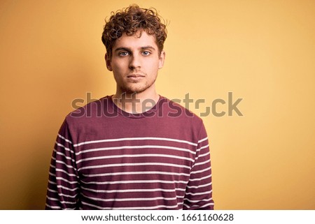 Young blond handsome man with curly hair wearing casual striped sweater depressed and worry for distress, crying angry and afraid. Sad expression.