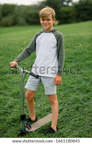 A front view portrait shot of a young boy playing on push scooter.