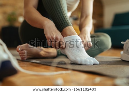 Close-up of sportswoman wearing white socks while preparing for workout at home.  Royalty-Free Stock Photo #1661182483
