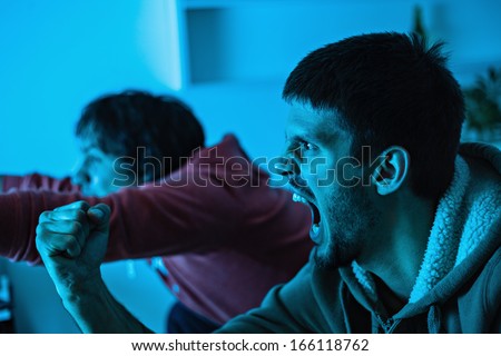 Two young men watching sports competition and drinking beer.