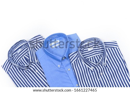 Three folded blue new men's blue, and striped shirts close-up isolated .top view 


