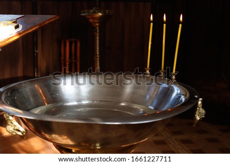 Metal basin (font) with three candles for bathing babies during the baptismal ceremony in the temple