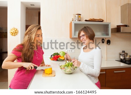 two girls animatedly chatting in the kitchen