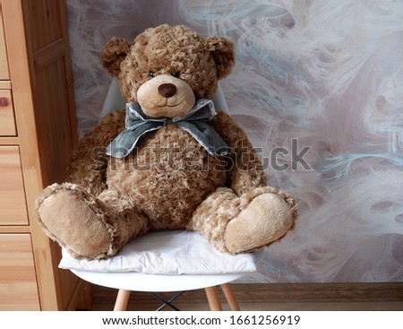 Soft toy bear with a bow sitting on a chair