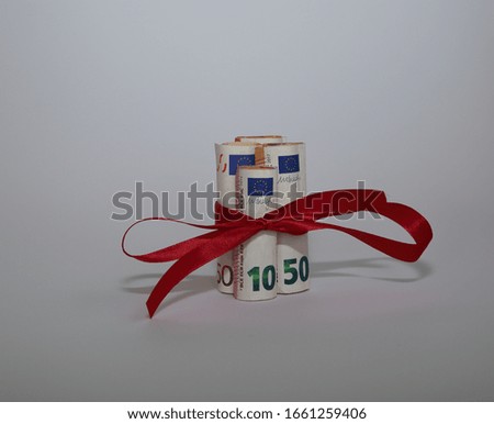 Banknotes of 10 and 50 euro rolled in rolls and tied with red ribbon, bow, on isolated on white background,  concept of economical / financial gift / present