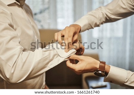 businessman dresses white shirt, male hands closeup,groom getting ready in the morning before wedding ceremony