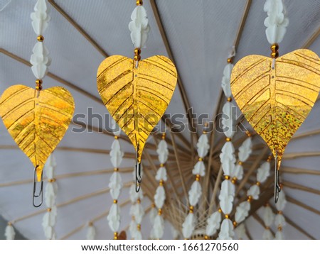 Bodhi golden (Bai Pho Thong) hanging on the white umbrella in the Thai temple. Used for hanging the money merit on Bodhi leaves. Represents Thai culture and Thai traditional