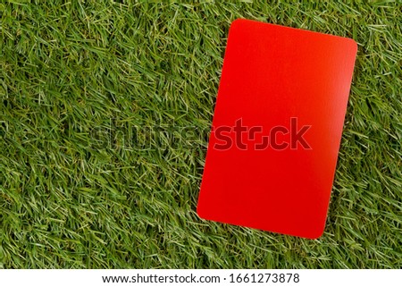 Soccer sports referee red card on grass background - penalty, foul or sports concept, top view flat lay from above