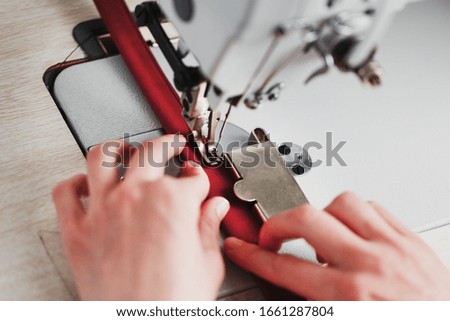 A leather craftsman produces leather goods on a sewing machine in his shop.