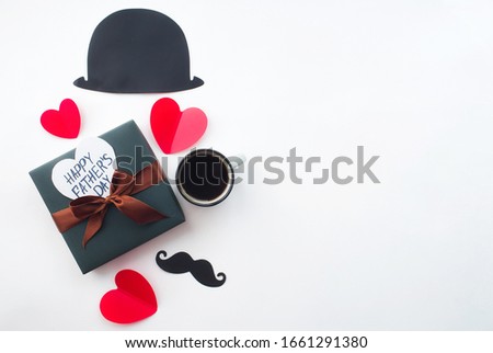 Father's Day Holiday Concept. Flatlay Hat, coffee mug, gift, red heart and a funny black mustache on an isolated white background. Copy space for inscriptions.
