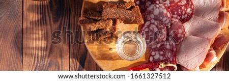 Traditional drink vodka in glasses, with a snack in the form of cold cuts and bacon, cucumbers, preservation. Russian festive national table.