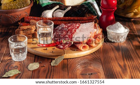 Traditional drink vodka in glasses, with a snack in the form of cold cuts and bacon, cucumbers, preservation. Russian festive national table.