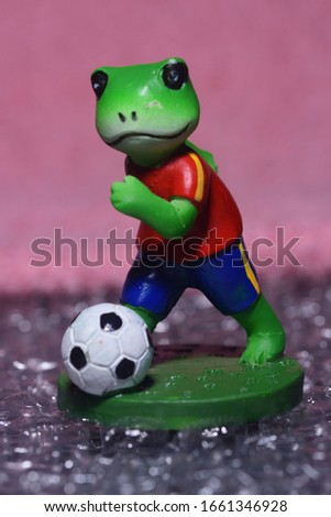 A toy Frog is kicking football