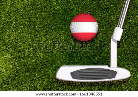 A golf club and a ball with flag Austria during a golf game.