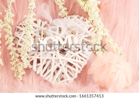Home decoration on pink fur background. Wooden heart with ribbon and word home, white flowers closeup picture.