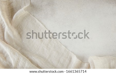 Pure washed linen cloth on light grunge stone background. Natural washed linen fabric on stone tile surface with copy space. Royalty-Free Stock Photo #1661365714