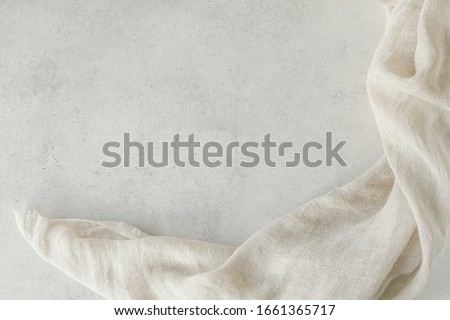Pure washed linen cloth on light grunge stone background. Natural washed linen fabric on stone tile surface with copy space. Royalty-Free Stock Photo #1661365717
