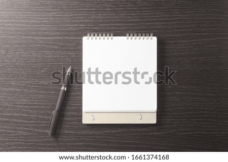 Empty stylish spiral Notepad for notes and a beautiful corporate pen on the background of a dark textured wood table. Empty space. Stylized stock photos. The view from the top.
