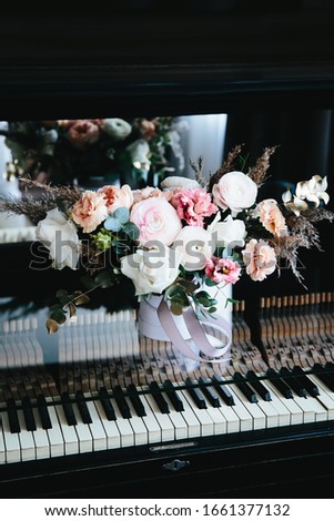 Light bouquet of flowers on the piano on a dark background
