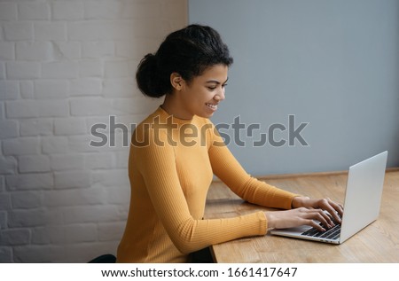 Beautiful woman copywriter working freelance project, typing, searching information on website. African American student studying using laptop computer and internet. Online education